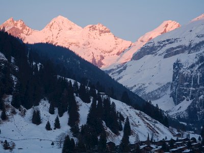 Alpenglow casted onto snowcapped mountains from balcony view in swiss village, Switzerland