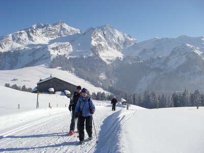 Ramble Worldwide walking group snowshoeing in Germany with alpine hut and mountains in background