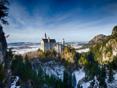 Neuschwanstein Castle viewed from distance surrounded by pine trees in wintry landscape, Germany