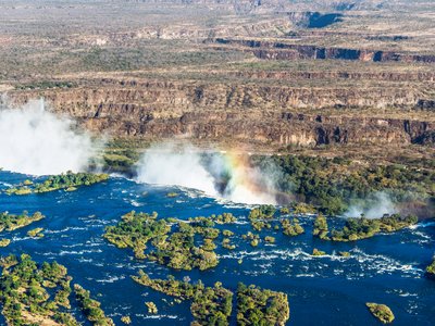 Aerial view of a rainbow over Victoria Falls waterfall on Zambezi River, border of Zambia and Zimbabwe