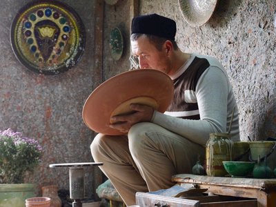 Man focussing on ceramic design in room of Gijduvan Ceramics Centre, Uzbekistan