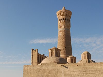Kalyan Minaret and domes against faint white clouds in blue sky, Bukhara, Uzbekistan