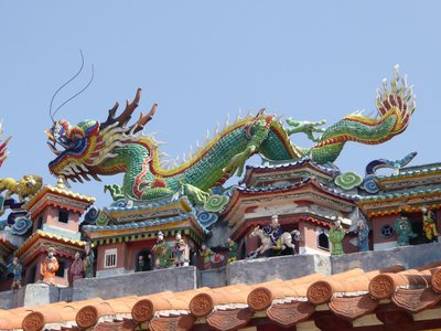 Large detailed colourful dragon statue on temple roof on clear blue sky sunny day, Hong Kong