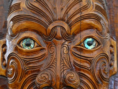 Maori traditional wooden sculpture of face with blue eyes, New Zealand