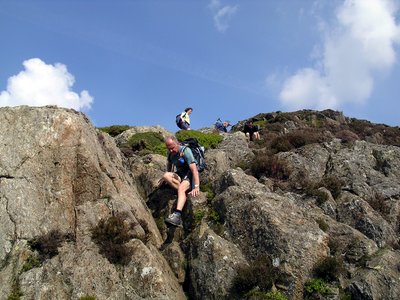 Man scrambling down rocks of Great Gable on sunny day, Buttermere