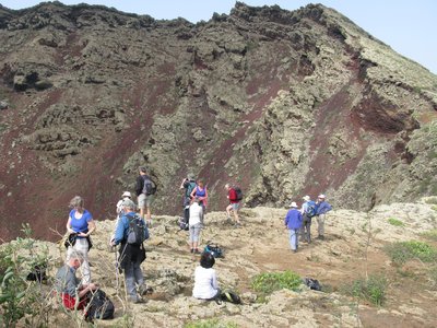 Ramble Worldwide walking group on walking holiday in Lanzarote taking a break to admire view of volcanic crater of Montana Corona, north Lanzarote, Spain