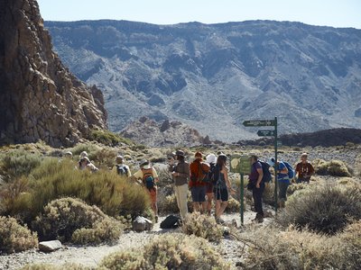 Ramble Worldwide walking group standing by signpost with mountain landscape in background, La Gomera, Canary Islands, Spain