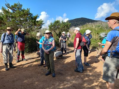 A group of people on Ramble Worldwide walking holiday Undiscovered Sardinia standing together on a dirt road, surrounded by greenery and open space