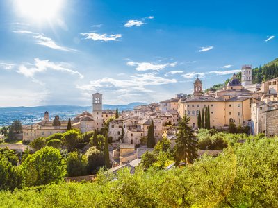 Panoramic view of the historic town of Assisi in bright morning light on a sunny day with blue sky and clouds in summer, Umbria, Italy