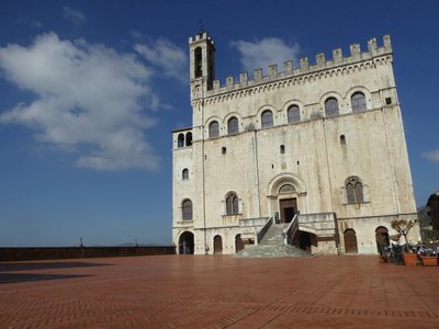 Distant shot of Palazzo Pretorio in Gubbio with blue skies and some cloud, Italy