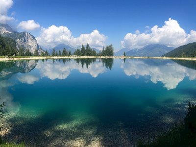 Lake at Ehrwalder Almsee with blue sky and white cloud reflection, Ehrwald, Tirol, Austria