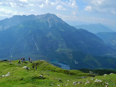 Ramble Worldwide walking holiday group on The Zugspitz Arena walking holiday standing by mountain edge admiring Grubigstein alps on sunny day, Austria