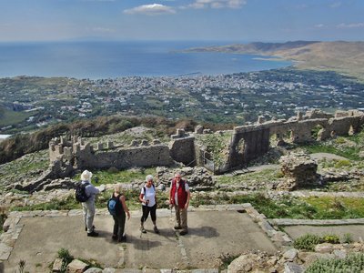 Group of four ramble worldwide people in Karystos from Castello Rosso with expansive view of landscape and sea behind them, Greece