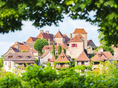 Village of Loubressac framed by green leaves on sunny day, France