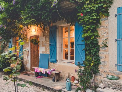 Traditional stone house with colourful facade consisting of blue window shutters and green vines growing over walls, in medieval town Rocamadour in France