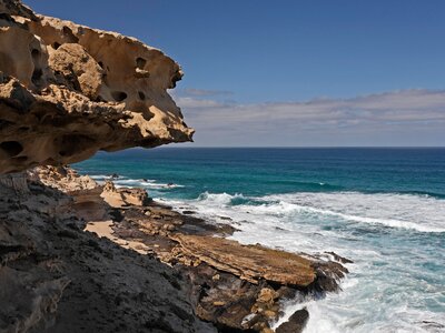 Coastal rock edge with white waves crashing nearby and blue sea, Isthmus - Istmo de la Pared, Playa de Barlovento, Fuerteventura, Canary Islands