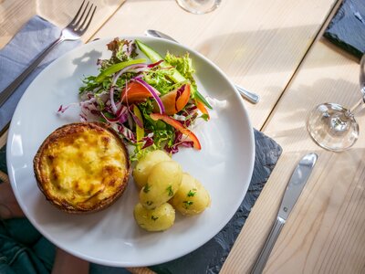 Close-up of dinnerplate with potatoes, salad, and pie on oak table at Hassness House