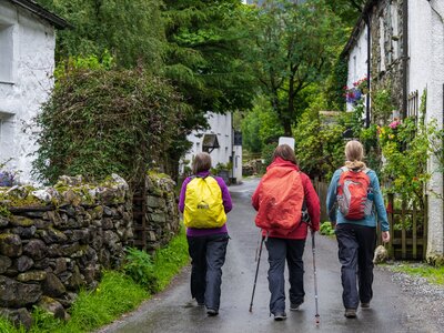 Ramblers Holiday walking trio of women passing through countryside village of Buttermere