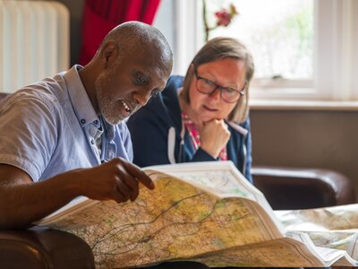 Two people from Ramble Worldwide walking holiday sat down looking at map in Hassness House living room