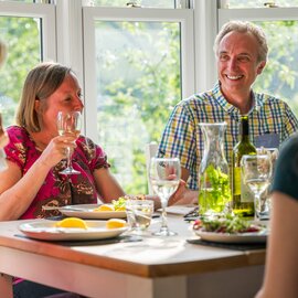 Walking group enjoying meal in sunlit dining room of Hassness House