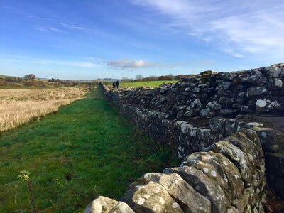 Two people walking along Hadrian's Wall in distance at Birdoswald Roman Fort