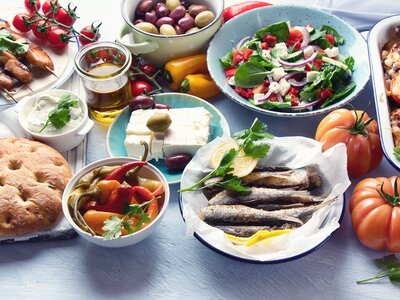Table displaying traditional Greek food including moussaka, meze, souvlaki, fish, pita, Greek salad, tzatziki, olives and vegetables
