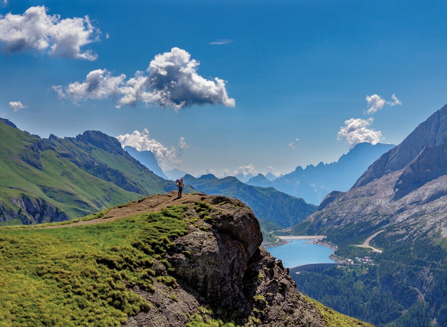 Solo walker near edge of cliff face taking in mountainous scenery, Dolomites, Italy, Europe
