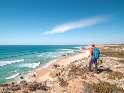 Traveller enjoys the view of the sandy beach of Praia do Malhao Sul on the Atlantic coast near Vila Nova de Milfontes, Odemira, Portugal.  In the footsteps of Rota Vicentina. Fisherman trail