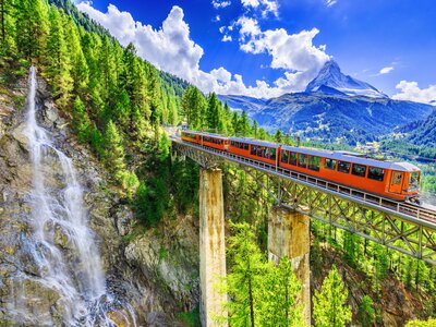 Gornergrat tourist train crossing bridge with waterfall to left and Matterhorn in background, Valais region, Zermatt, Switzerland