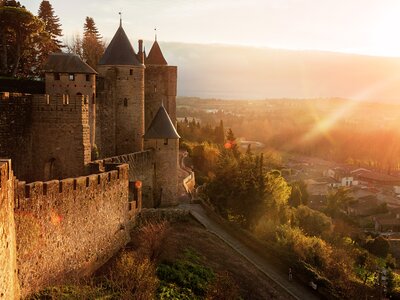 Carcassonne fortress atop hill overlooking city with warming sun shining over brickwork, France