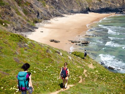 People walking down hill towards sandy beach on Fisherman Trail enjoying coastal scenery whilst on walking holiday, Vicentina, Portugal