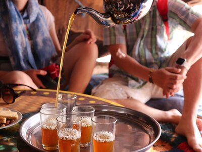 Close up of traditional Moroccan tea being poured into glass beneath shaded seating area in Morocco