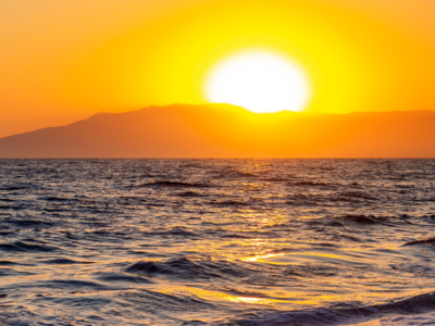 Radiant sunset disappearing behind mountains with golden glow glistening across the sea viewed from beach of Cabo de Gata, Cabo de Gata-Níjar Natural Park, Spain