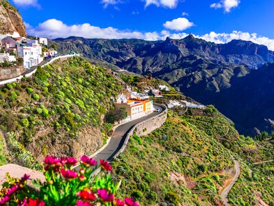 View of Artenara Village nested into mountainside on green bush hills amidst large mountain range, Gran Canaria, Spain
