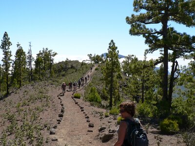 Walking group passing through dirt pathway atop mountain in La Palma, Spain