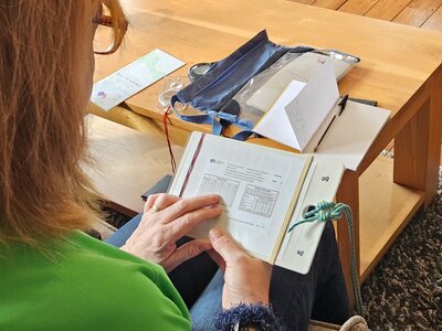 Lady from Ramble Worldwide navigation skills course reading Ordinance Survey timing card in Hassness Country House living room