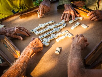 Elderly men playing dominoes on sunlit table, Cuba