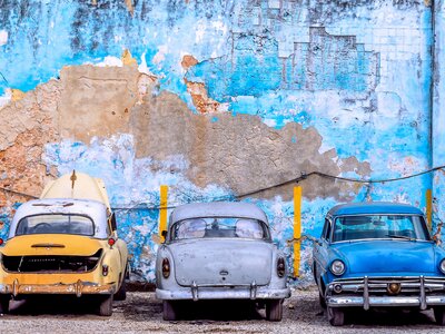 Old classic cars parked by blue faded and worn wall, Havana, Cuba, Caribbean