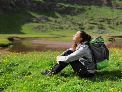 Hiker resting and breathing fresh air sitting on the grass in nature