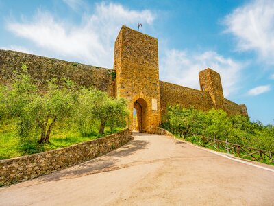 Hill leading to stone archway entrance into medieval town Monteriggioni, Tuscany, Italy, Europe