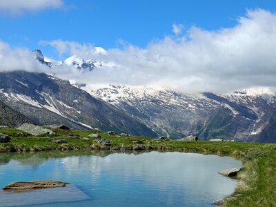 Lake of Kreuzboden with snow-capped alps in background and clouds with blue sky, Saas-Grund, Switzerland