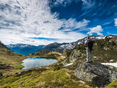 Active hiker with backpack in Pyrenees overlooking lake Tristaina in Andorra