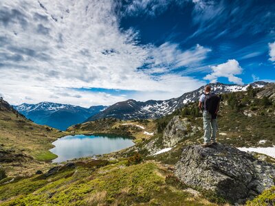 Active hiker with backpack in Pyrenees overlooking lake Tristaina in Andorra
