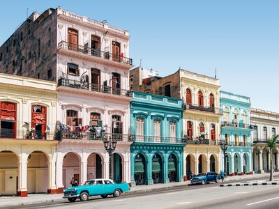 Colourful facades with old classic cars parked outside on sunny day, Cuba
