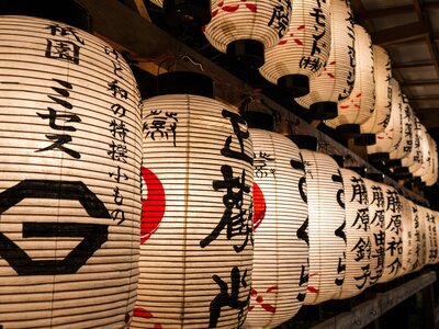 Close up of paper lanterns emanating light from within and decorated with Japanese calligraphy in black and red ink, Yasaka Shrine in Kyoto, Japan
