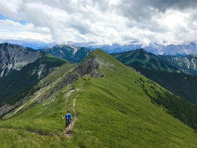 Hiker walking along ridge walk near mount Kienjoch, Graswang, Bavaria, Germany