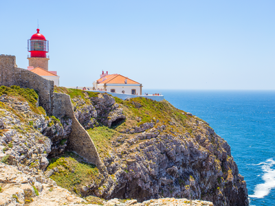 View of the lighthouse at Cabo de Sao Vicente on sunny blue sky day with Atlantic ocean in background, Algarve, Portugal