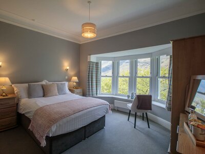 Hassness House bedroom interior mixed with natural and artificial lighting to create a cosy and comfortable atmosphere with large windows looking onto Buttermere Lake in the Lake District