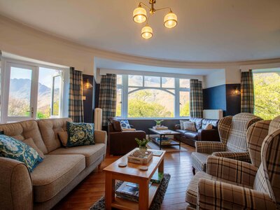 Hassness House living room with matching tartan chairs and curtains and large windows with views onto lake Buttermere, Ramble Worldwide Lake District country house