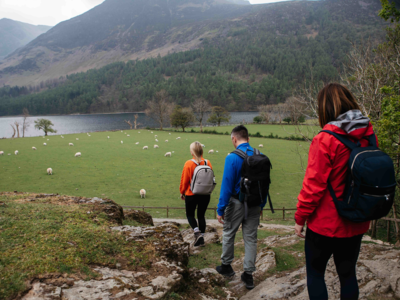 People descending rocky pathway with Buttermere Lake in distance